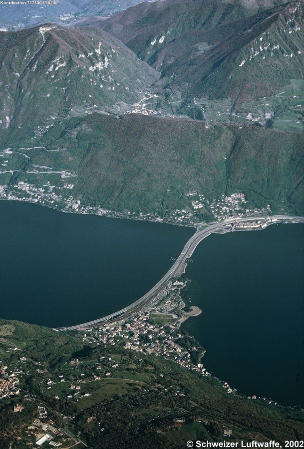 Damm von Melide (1975); im Vordergrund: Melide, dahinter 'Swiss Miniatur'. Bissone am andern Ende des Damms. Ort links: Campione. Oben auf dem Berg: Arogno (CH) und der 'Dogana Madonna di Valmara'.